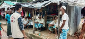 写真③：マーケットに集う人々に適切な距離について実演しながら説明する保健ワーカー